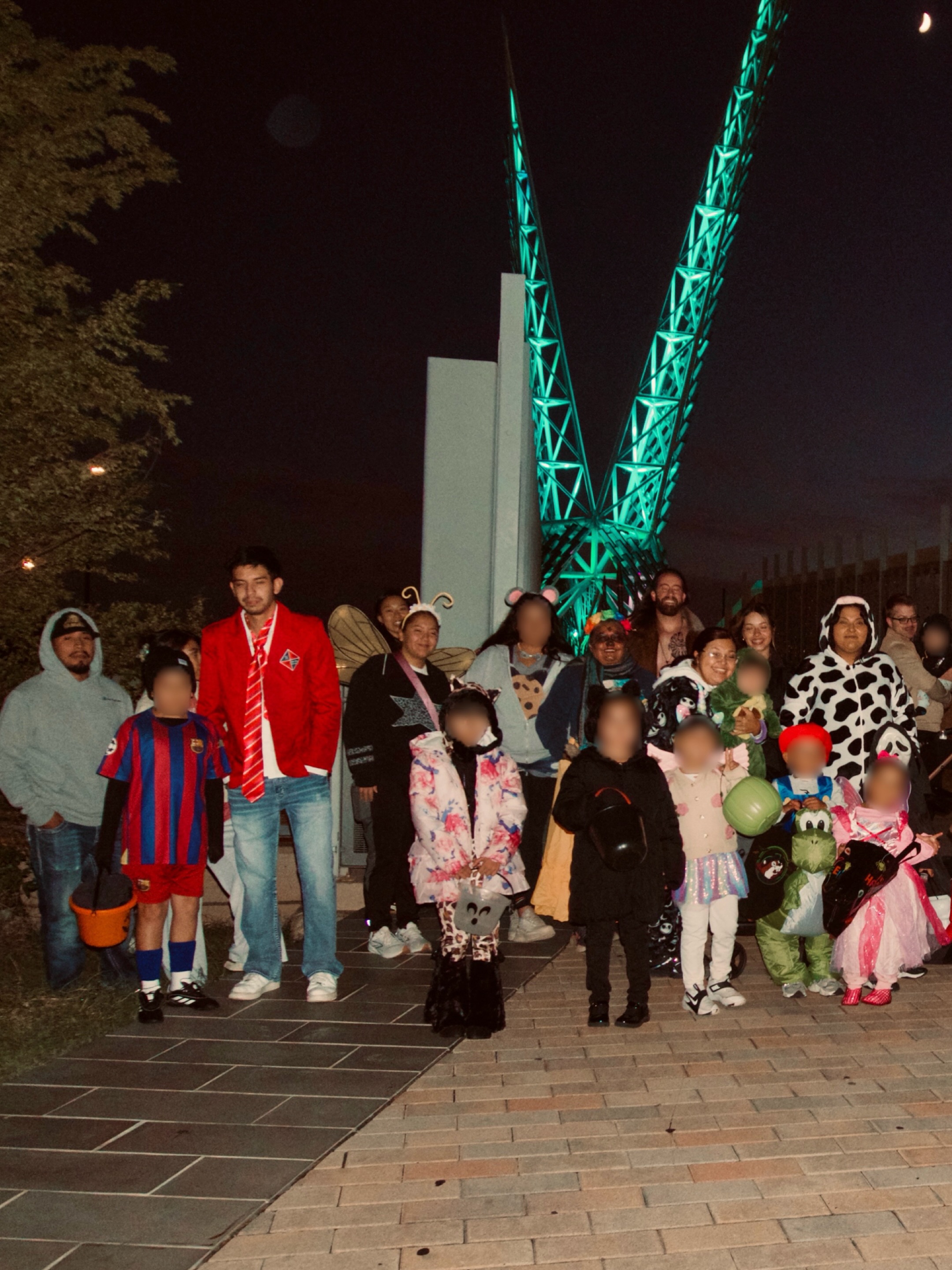 Families in Halloween costumes gathered at Scissortail Park; original photographer-applied face blurring preserved